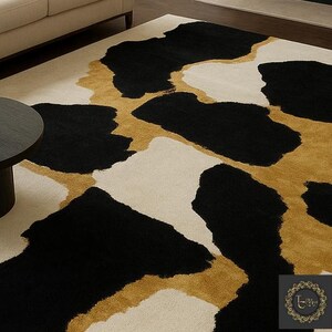 May include: A large area rug with a bold, abstract design. The rug features large, irregular shapes in black, gold, and cream. The pattern creates a striking contrast, suitable for a modern living space. The rug is made of a soft, plush material.