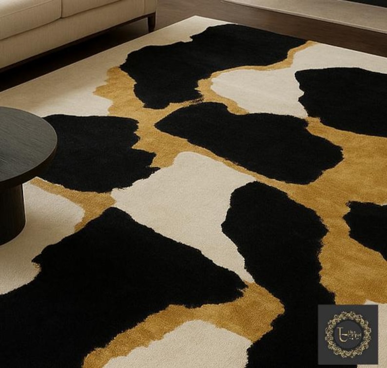 May include: A large area rug with a bold, abstract design. The rug features large, irregular shapes in black, gold, and cream. The pattern creates a striking contrast, suitable for a modern living space. The rug is made of a soft, plush material.