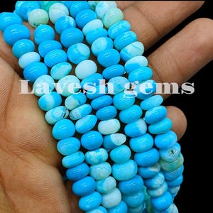 May include: A strand of round, smooth, bright blue beads with white marbled patterns. The beads are arranged in multiple vertical rows, displaying a consistent circular shape and a polished finish. The text Lavesh gems is overlaid in white.