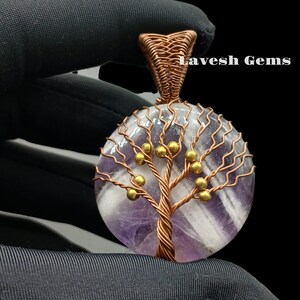May include: A wire-wrapped amethyst pendant featuring a tree of life design with gold beads. The pendant is made with copper wire and has a round shape.