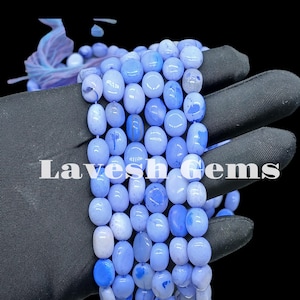 May include: A strand of blue agate beads with a white and blue marbled pattern. The beads are round and smooth, and they are strung on a clear elastic cord.