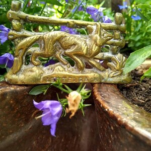 May include: A brass figurine of a fox running through a fence, with the word "Zeiterfax" inscribed on the base. The figurine is sitting on a brown planter.