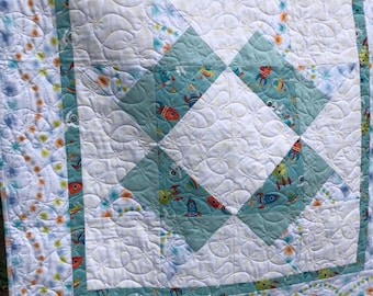 Spacemen Baby Quilt: Cotton patchwork  made from material with spacemen and rockets pattern.