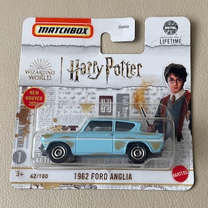 Könnte beinhalten: Ein Matchbox-Modellauto des 1962 Ford Anglia in Hellblau mit Rostakzenten, aus der Harry Potter Wizarding World-Serie. Die Verpackung zeigt Harry Potter und den Text "NEW NOUVEAU 2024".
