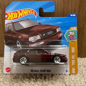 May include: A red 1994 Audi Avant RS2 Hot Wheels car in a plastic package. The package has a blue background with the Hot Wheels logo and the text 'HW: '70s VS. '90s'.