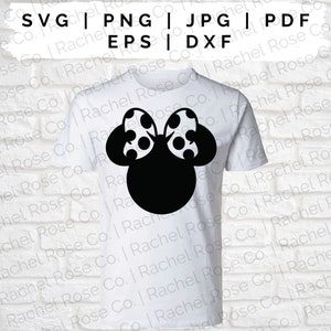 K&ouml;nnte beinhalten: Ein wei&szlig;es T-Shirt mit einer schwarzen Silhouette eines M&auml;usekopfes mit einer gepunkteten Schleife. Der M&auml;usekopf ist mittig auf dem T-Shirt platziert.