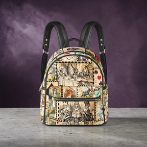 May include: A black backpack with a design featuring illustrations from Alice in Wonderland, such as the Mad Hatter's tea party and the Queen of Hearts. It has black straps and a zippered front pocket. The design is printed on a beige background.
