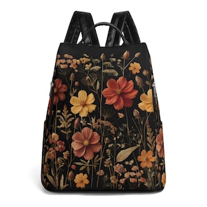 Puede incluir: Mochila negra con un diseño floral de flores naranjas, amarillas y rojas. La mochila tiene correas negras y un asa superior. El estampado floral cubre la parte delantera de la mochila.