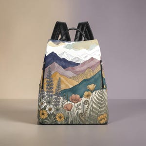 May include: A rucksack with a watercolour landscape design featuring mountains, flowers, and foliage. The rucksack has black straps and zips, and the design includes shades of blue, purple, yellow, and green.