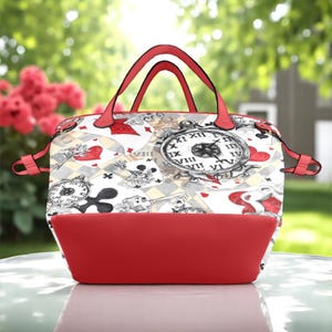 Puede incluir: Un bolso de mano rojo y blanco con un dise&ntilde;o caprichoso que presenta cartas de juego, relojes y llaves. El bolso tiene un fondo rojo y dos asas superiores.