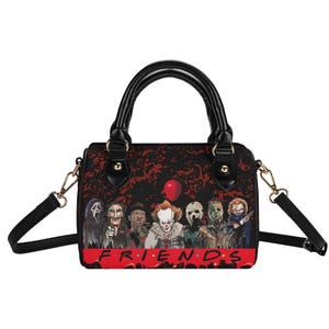 Puede incluir: Bolso de mano negro con asa superior y correa para el hombro desmontable. El bolso presenta un gráfico de personajes de películas de terror y la palabra "FRIENDS" en rojo. El fondo es un patrón rojo oscuro.