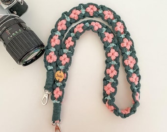 May include: A camera strap made of dark green, light blue, and pink cord in a braided pattern. The strap features a small, round wooden tag engraved with the name Jade and includes silver-colored metal swivel clips at both ends.