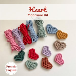 Puede incluir: Un kit de macramé con el texto "Heart Macramé Kit" incluye paquetes de cordón rosa, morado, rojo, azul y verde. También se muestran varias piezas de macramé en forma de corazón en varios colores, incluyendo azul, dorado, marrón, verde, rojo, morado y rosa.
