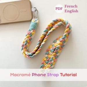 Peut inclure: Une lanière de téléphone macramé tressée aux couleurs pastel jaune, rose et bleu, attachée à un étui de téléphone. La lanière est tressée et possède un fermoir argenté. Le texte "Macramé Phone Strap Tutorial" est affiché.