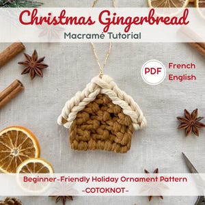 May include: A macramé gingerbread house ornament featuring a brown knotted body and a cream-coloured braided roof with a hanging string. The text reads: Christmas Gingerbread Macramé Tutorial, PDF, French, English, Beginner-Friendly Holiday Ornament Pattern, -COTOKNOT-.