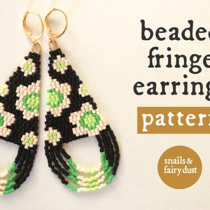 May include: Beaded fringe earrings pattern by snails & fairy dust. The earrings are black, white, and green with a geometric pattern of flowers. The earrings are hanging from gold hoops.