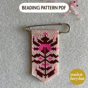 May include: A rectangular beaded charm attached to a silver-toned metal safety pin. The beadwork features a symmetrical floral pattern in shades of cream, dark maroon, and bright pink. The text BEADING PATTERN PDF appears at the top.