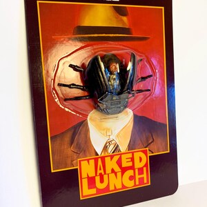 Puede incluir: Figura de acci&oacute;n de un escarabajo con sombrero y traje, empaquetada en una tarjeta retro. La tarjeta presenta el texto "NAKED LUNCH" en naranja y el logotipo "SPEAR'S TOYS". El embalaje es de color granate oscuro.