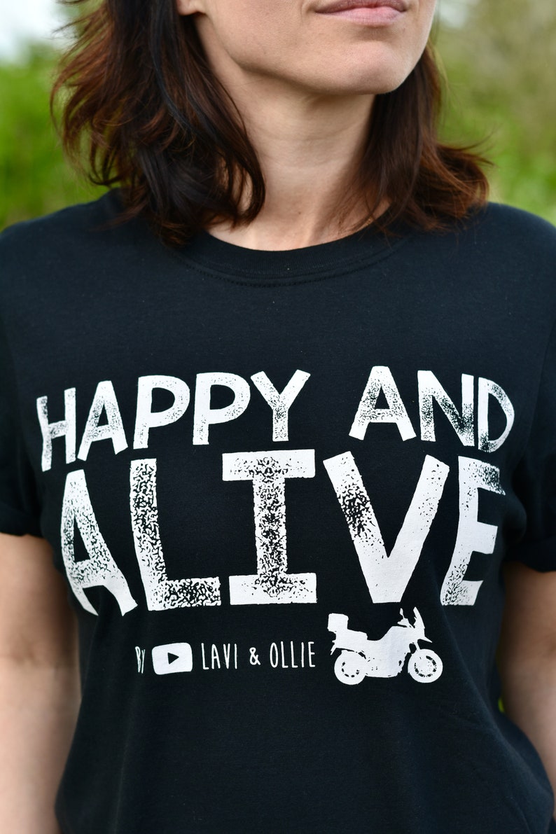 May include: Black t-shirt with white text that reads "HAPPY AND ALIVE" with a motorcycle graphic and the text "#  LAVI & OLLIE" below.