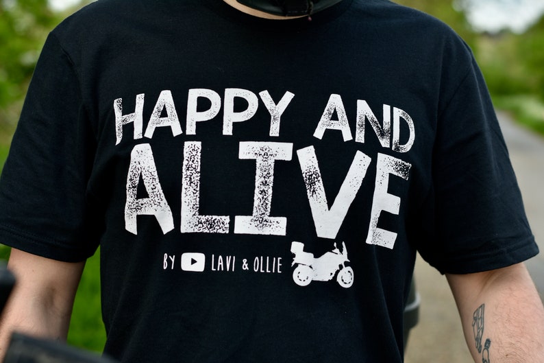 May include: Black t-shirt with white text that reads "Happy and Alive" with a small motorcycle graphic and the text "By YouTube Lavi & Ollie".