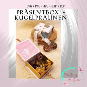 May include: A set of two small gift boxes with lids. The boxes are decorated with a pink and white polka dot pattern, a gold and white star pattern, and a white silhouette of a fairy. The boxes are filled with chocolate candies. The text "Präsentbox ~ Kugelpralinen" and "Firlefanz de Luxe" is visible on the image.