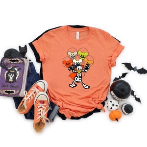 May include: Orange t-shirt with a black and white illustration of a skeleton Mickey Mouse holding a bunch of orange, yellow, and green balloons with Mickey Mouse faces. The balloons have spooky expressions.