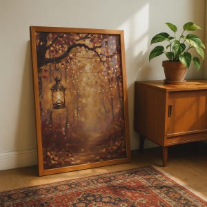 May include: A framed rectangular wall art print featuring an oil painting of a forest path during autumn. A glowing lantern hangs from a tree branch, illuminating the surrounding golden and brown foliage. String lights are draped through the trees.