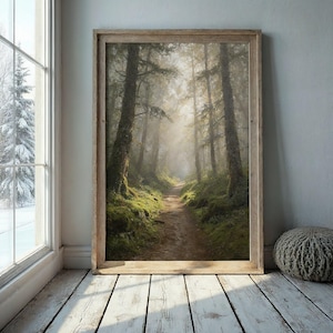 Könnte beinhalten: Ein gerahmter Druck eines Waldweges. Das Bild zeigt einen Feldweg, der sich durch einen grünen Wald mit hohen Bäumen und Moos schlängelt. Sonnenlicht filtert durch die Bäume und erzeugt einen nebligen Effekt. Der Rahmen ist aus hellem Holz.