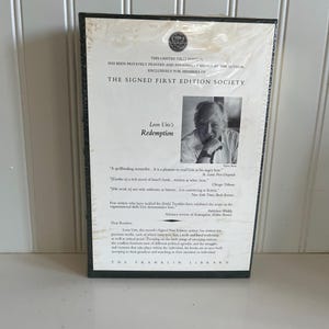 May include: A black and white photo of Leon Uris, the author of the book "Redemption." The book cover features a quote from the Chicago Tribune: "His work is not only authentic as history, it is convincing as fiction." The book is part of The Signed First Edition Society.