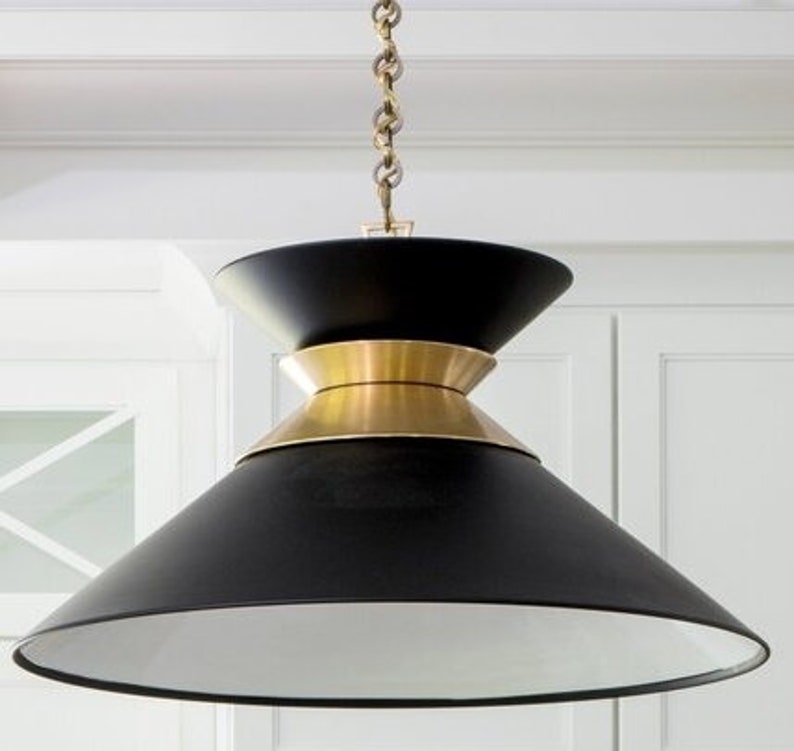 May include: A black and gold pendant light with a wide, cone-shaped shade. The shade has a white interior and a brass trim.
