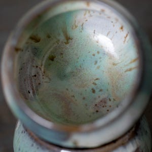 K&ouml;nnte beinhalten: Eine handgefertigte Keramikschale mit einer einzigartigen Glasur. Das Innere zeigt eine Mischung aus hellblauen, gr&uuml;nen und braunen Farbt&ouml;nen, die einen Marmoreffekt erzeugen. Der Rand der Schale ist heller und setzt einen Kontrast.