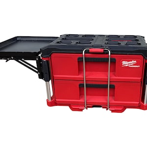 May include: A red and black Milwaukee Packout tool box with two drawers and a fold-down work surface. The tool box has a black handle and a silver latch.