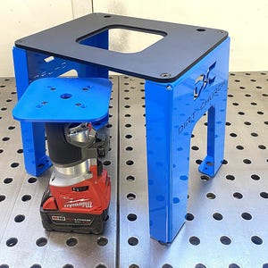 May include: A blue and black router table with a red and black power tool. The table has a square top with a cutout and is supported by blue legs. The text "DIRT CHURCH" is visible on the side.