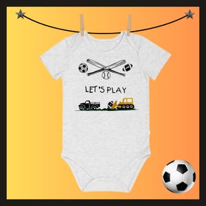 May include: A white baby onesie with a graphic design featuring a soccer ball, baseball bat, baseball, football, and the text "LET'S PLAY." Below are illustrations of a truck and a construction vehicle.