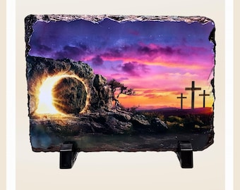 May include: A stone plaque with a colorful sunset scene depicting a stone tomb with a glowing light emanating from it. Three crosses are silhouetted against the sunset in the background.