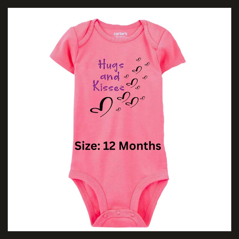Pode incluir: Um body rosa para beb&eacute; com mangas curtas. O body tem as palavras "Hugs and Kisses" em roxo e preto, com gr&aacute;ficos de cora&ccedil;&otilde;es. O tamanho &eacute; 12 meses.