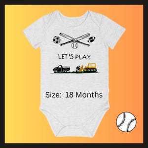 May include: A light gray baby onesie with a sports-themed graphic. The design includes crossed baseball bats, a soccer ball, a baseball, and a football. The text "LET'S PLAY" is above a truck, a football, and a construction vehicle. The size is 18 months.