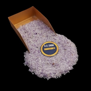 Könnte beinhalten: Eine kleine goldene Schaufel gefüllt mit hellvioletten Amethystkristallen. Die Kristalle sind klein und haben eine Größe von 0,5 bis 2 mm. Ein Etikett auf der Schaufel lautet "0,5-2MM".