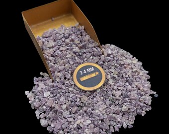May include: A scoop of purple amethyst gemstone chips, ranging in size from 2-4 mm, in a small gold-colored metal scoop. The chips are loose and scattered around the scoop.