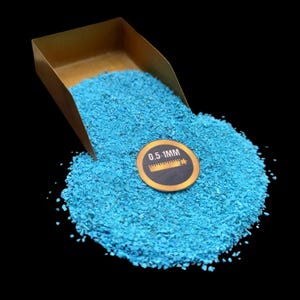 May include: A small gold scoop filled with turquoise blue crushed stone. A label on the stone reads "0.5-1MM".