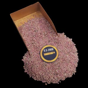 Pode incluir: Um close-up de uma pá cheia de pedra triturada rosa. A pedra é etiquetada como "0,5-2 MM".