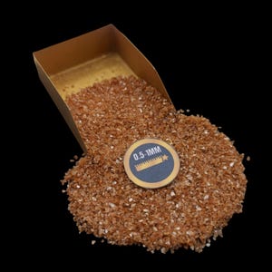 May include: A gold pan filled with brown, orange, and white glitter. The glitter is labelled as 0.5-1MM.
