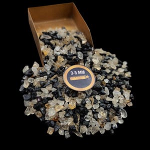 May include: A pile of mixed gemstones, including black, clear, and amber-colored stones, is shown with a small scoop. A circular label indicates the stones are 3-5 mm in size. The background is black.