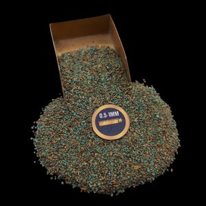 May include: A pile of small, irregularly shaped stones in shades of brown and turquoise, with a scoop partially visible at the top. A circular sticker indicates the size as 0.5-1mm. The stones are scattered on a black background.