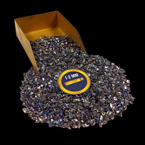May include: A pile of iridescent, dark-colored crushed glass, with a small gold-colored scoop. A circular sticker indicates the glass pieces are 1-3 mm in size. The glass has a reflective, textured appearance.