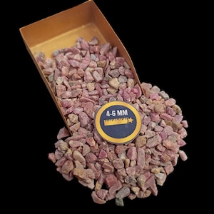 Pode incluir: Um close-up de um monte de lascas de rubi rosa em uma bandeja marrom. As lascas são de vários tamanhos, variando de 4 a 6 mm.