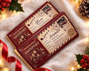 May include: Two rectangular chocolate bars wrapped in custom paper designed to look like North Pole passports. The dark red covers feature vintage-style graphics, including a globe, reindeer silhouettes, and text reading North Pole Passport.