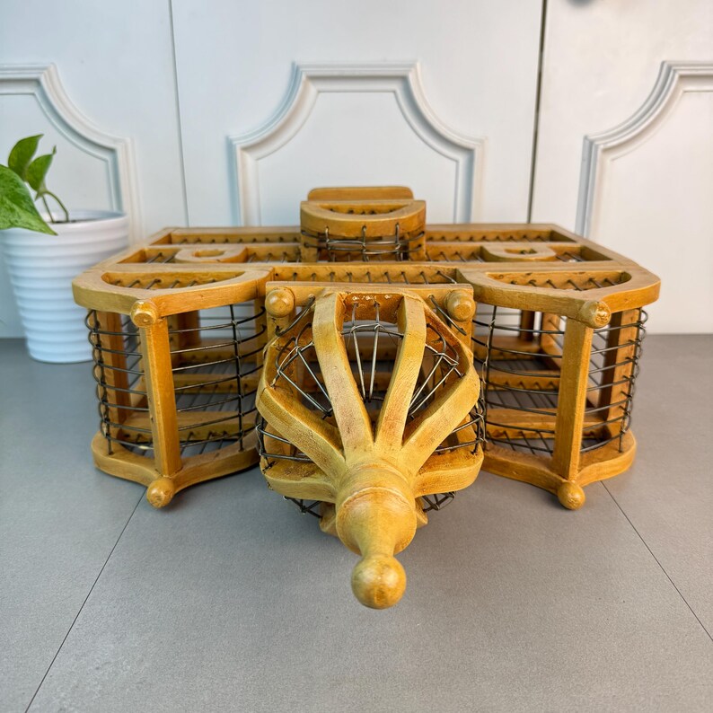 May include: A wooden birdcage with a decorative, ornate design. The cage is made of light brown wood and has a wire mesh interior. The cage has a pointed top and a decorative finial.