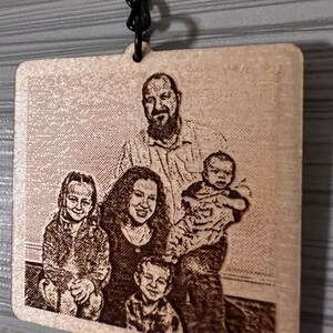 Peut inclure: Un porte-cl&eacute;s en bois avec une image grav&eacute;e au laser d'une famille de cinq personnes. La famille sourit et semble &ecirc;tre dans un cadre familial. Le porte-cl&eacute;s est attach&eacute; &agrave; une cha&icirc;ne en m&eacute;tal noir.