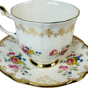 Peut inclure: Service à thé blanc avec des détails dorés et des motifs floraux. La tasse a une anse incurvée et des bordures dorées. La soucoupe a un bord festonné et un motif floral assorti. Un service à thé classique.